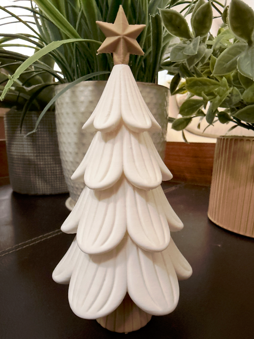 White Petal Pine Tree with tan star on a table with plants